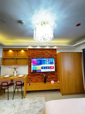 a living room with a table and a tv on a brick wall at European Inspired Shore 2 Residences in Manila