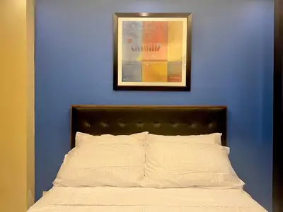 a bed with a blue wall with a picture above it at 5Q Place Hotel Manila Airport in Manila