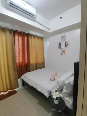 a bedroom with a bed and a tv and curtains at Jazz Apartment Unit in Manila