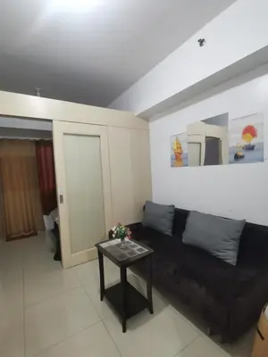 a living room with a black couch and a table at Jazz Apartment Unit in Manila