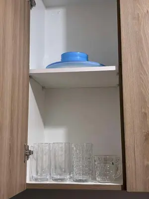 a cupboard with glasses and a blue bowl on it at Shore 2 Residences Mall of Asia staycation in Manila