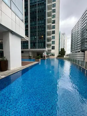 a large swimming pool in a building with tall buildings at Rustic Elegance New One Bedroom One Uptown Free parking in Manila