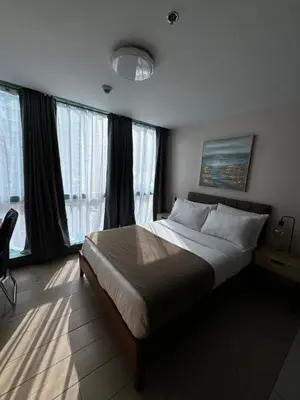 a bedroom with a large bed and large windows at Rustic Elegance New One Bedroom One Uptown Free parking in Manila