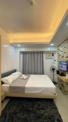 a bedroom with a large bed and a television at Cozy Condo Beacon Tower Makati in Manila