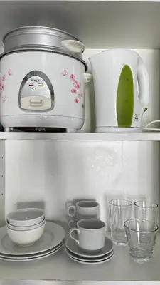 a kitchen shelf with a toaster and plates and cups at Cozy Condo Beacon Tower Makati in Manila