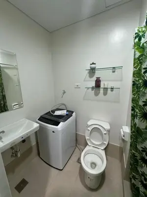 a white bathroom with a toilet and a sink at Bloom Residences by Casa Stellar in Manila