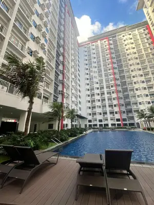 a large apartment building with a pool in front of it at Bloom Residences by Casa Stellar in Manila