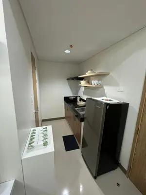 a small kitchen with a black refrigerator and a counter at Bloom Residences by Casa Stellar in Manila