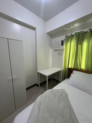 a bedroom with a bed and a green curtain at Bloom Residences by Casa Stellar in Manila