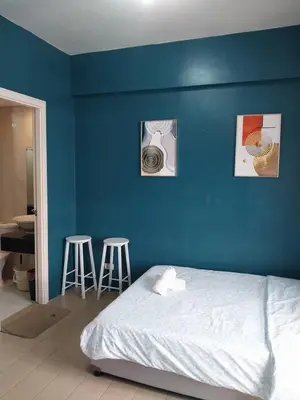 a bedroom with a blue wall with a bed and two stools at 150 Newport Blvd Condotel near T3 by Alps in Manila