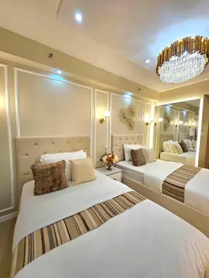 a large bedroom with two beds and a chandelier at Jay Suite in Manila