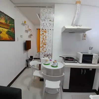 a white kitchen with a table and white chairs at Birch Tower by the Bay Studio type in Manila