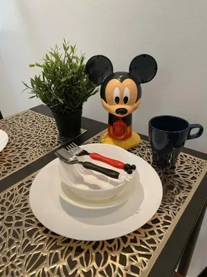 a table with a plate with a mickey mouse bowl and utensils at 1BR Mickey Mouse Theme BGC Forbeswood Parklane in Manila
