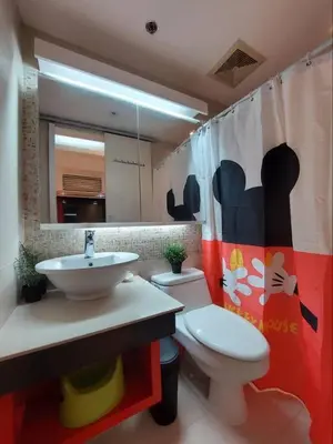 a bathroom with a sink and a toilet and a mirror at 1BR Mickey Mouse Theme BGC Forbeswood Parklane in Manila