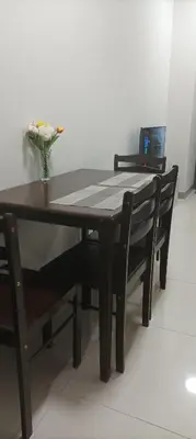 a dining room table with two chairs and a vase of flowers at Charlie's Penthouse in Mall of Asia Complex in Manila