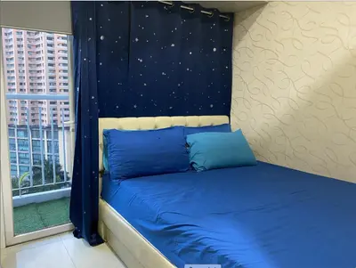 a bed with blue pillows in a room with a window at Cozy 1BR Condo at SM Lights Mandaluyong City in Manila