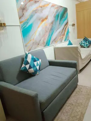 a living room with a couch and a painting at Dmjs staycation in Manila