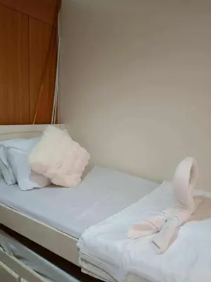 a bed with white sheets and pink shoes on it at Dmjs staycation in Manila