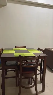 a wooden table with chairs and a table with green squares on it at Dmjs staycation in Manila