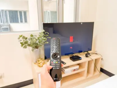 a person holding a remote control in front of a tv at Prime Condo Living Near Venice Canal #msert26k in Manila