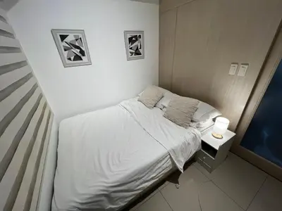 a small bedroom with a bed and a side table at Makati High rise 1 Bedroom Condo with Balcony in Manila