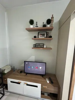 a living room with a television on a wooden table at Makati High rise 1 Bedroom Condo with Balcony in Manila