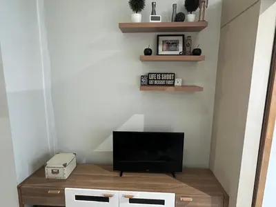 a living room with a television and shelves at Makati High rise 1 Bedroom Condo with Balcony in Manila