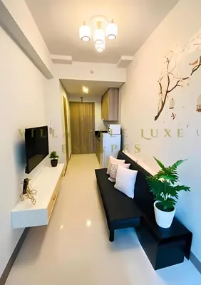 a living room with a black couch and a tv at 1 Bed Room Coast Residence at Heart of Metro Manila - Pasay City in Manila