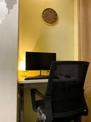 a desk with a computer and a clock on the wall at Azure Staycation by the clouds in Manila