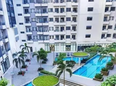 a large apartment building with a swimming pool and palm trees at Golden Scape 1 Bedroom near NAIA Airport in Manila