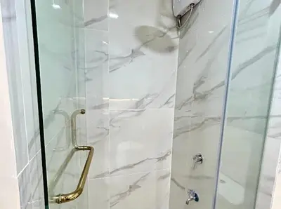 a bathroom with a shower with a glass door at Golden Scape 1 Bedroom near NAIA Airport in Manila