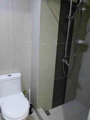 a bathroom with a shower and a toilet in it at Breeze Residences in Manila