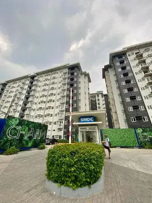 a woman walking in front of a large building at MG Place -2 BR condo unit at SMDC Charm Residences, Cainta, Rizal, 1900 in Cainta