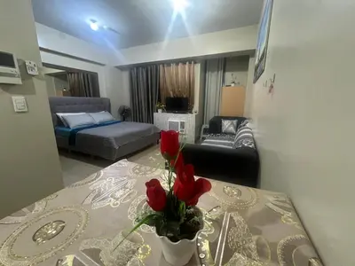 a living room with a table with a vase with red roses at one palm tree villas &two palm tree villas in Manila
