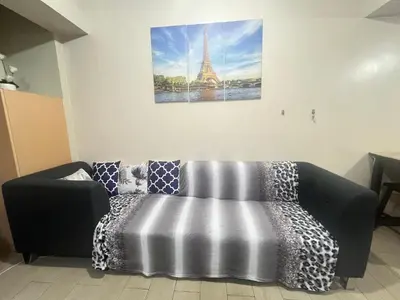 a couch in a room with a picture of the eiffel tower at one palm tree villas &two palm tree villas in Manila