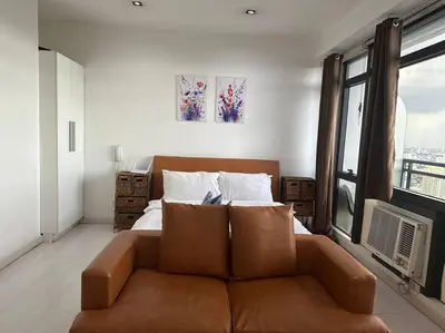 a living room with a couch in front of a bed at Gramercy Studio on 52nd Floor Rockwell View Free WiFi in Manila