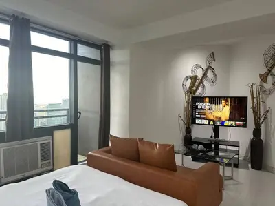 a living room with a couch and a television at Gramercy Studio on 52nd Floor Rockwell View Free WiFi in Manila