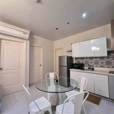 a kitchen with a glass table and white chairs at Gramercy Residences Two Bedroom on 60th Floor in Manila