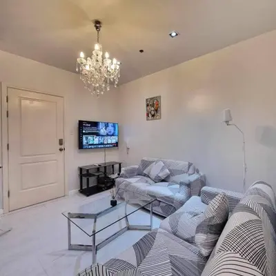 a living room with a couch and a chandelier at Gramercy Residences Two Bedroom on 60th Floor in Manila
