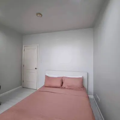 a white room with a bed with a pink blanket at Gramercy Residences Two Bedroom on 60th Floor in Manila