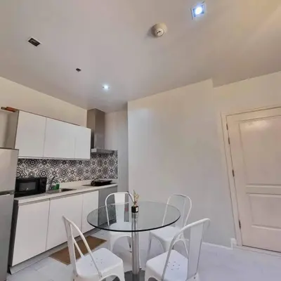 a kitchen with a glass table and white chairs at Gramercy Residences Two Bedroom on 60th Floor in Manila
