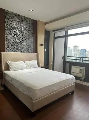 a bedroom with a large white bed with a large window at Spacious 1 Bedroom in Gramercy 2 balconies in Manila