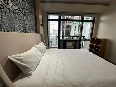 a bedroom with a white bed with a large window at Spacious 1 Bedroom in Gramercy 2 balconies in Manila