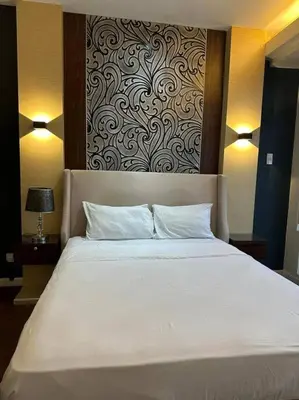 a large white bed in a room with a wall at Spacious 1 Bedroom in Gramercy 2 balconies in Manila