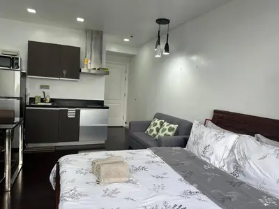 a bedroom with a bed and a couch and a kitchen at Gramercy Studio with City View fast WIFI Free use of Amenities in Manila