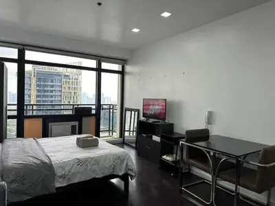 a bedroom with a bed and a desk with a television at Gramercy Studio with City View fast WIFI Free use of Amenities in Manila
