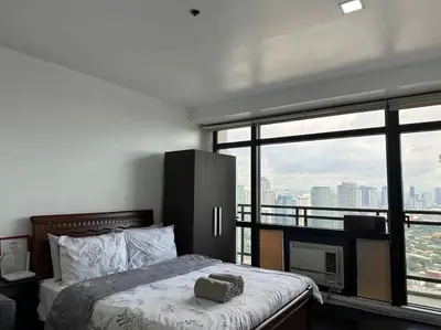 a bedroom with a bed and a large window at Gramercy Studio with City View fast WIFI Free use of Amenities in Manila