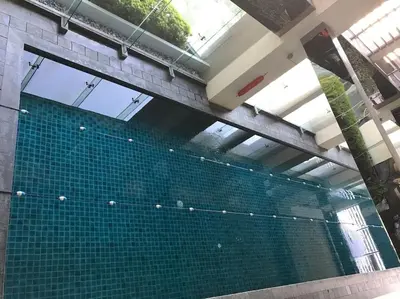 a swimming pool with green tiles in a building at Spacious Corner 1 Bedroom with Balcony Gramercy in Manila
