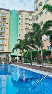 a swimming pool with palm trees in front of a building at Tessa's Place Staycation 10FI in Jalang