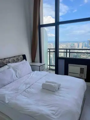 a white bed in a room with a large window at 64F Spacious 1 BR Nice View Pool Sauna Gym in Manila